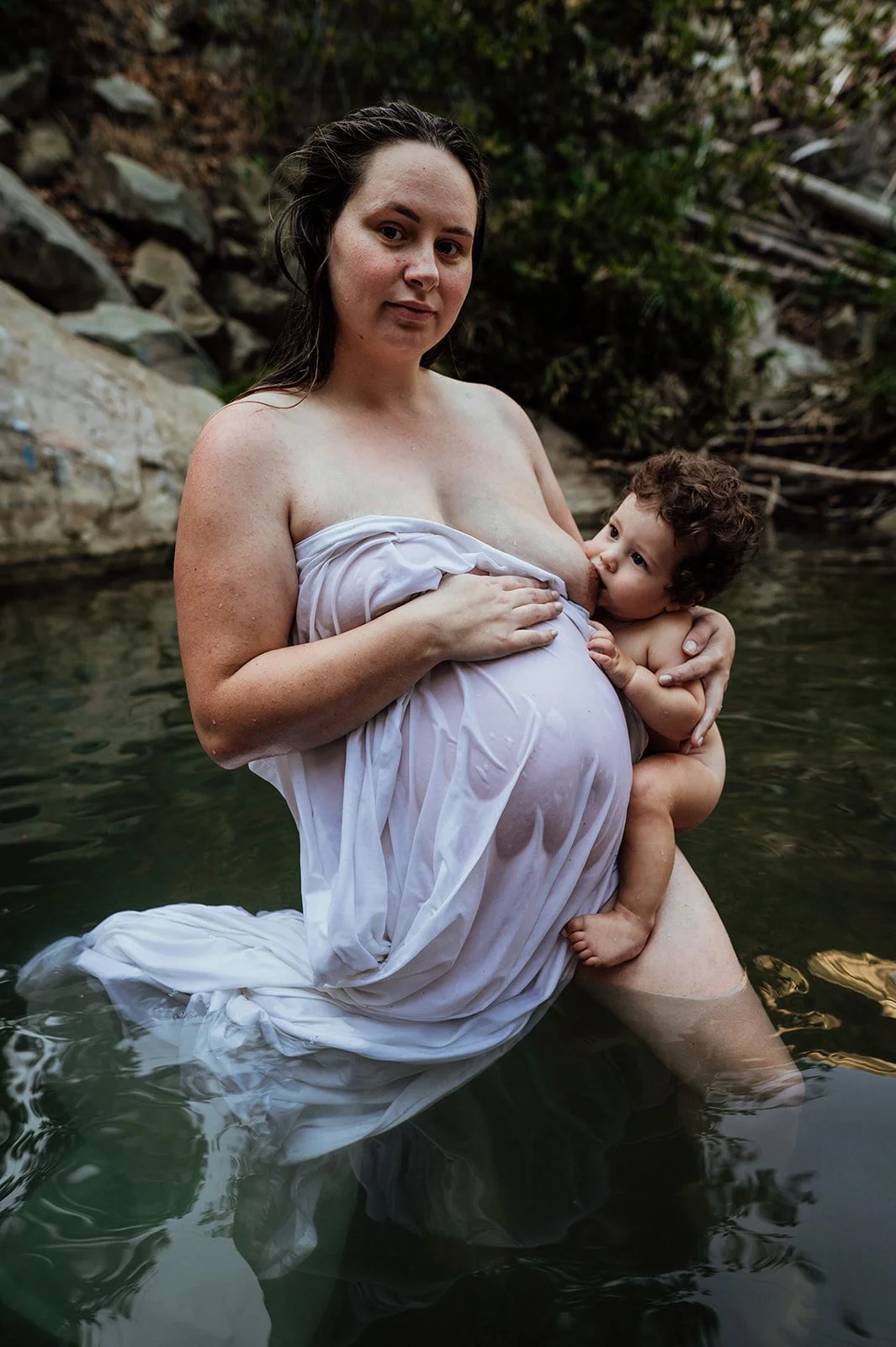 Maternity session with mom in river nursing her toddler.