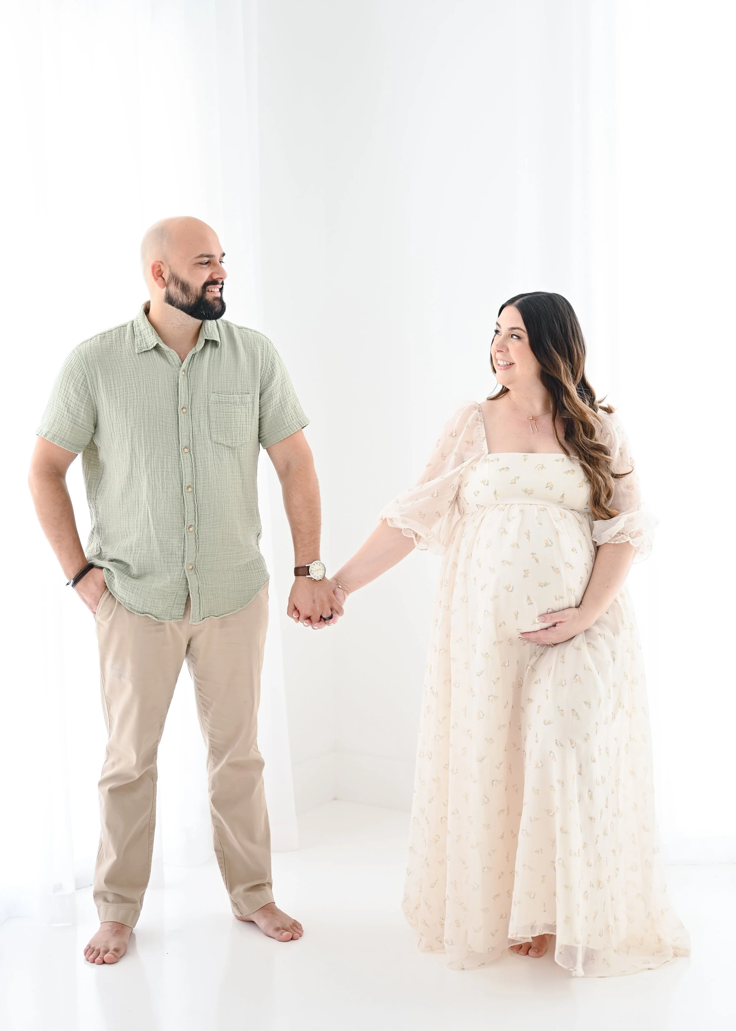 Parents holding their newborn baby on bench in studio
