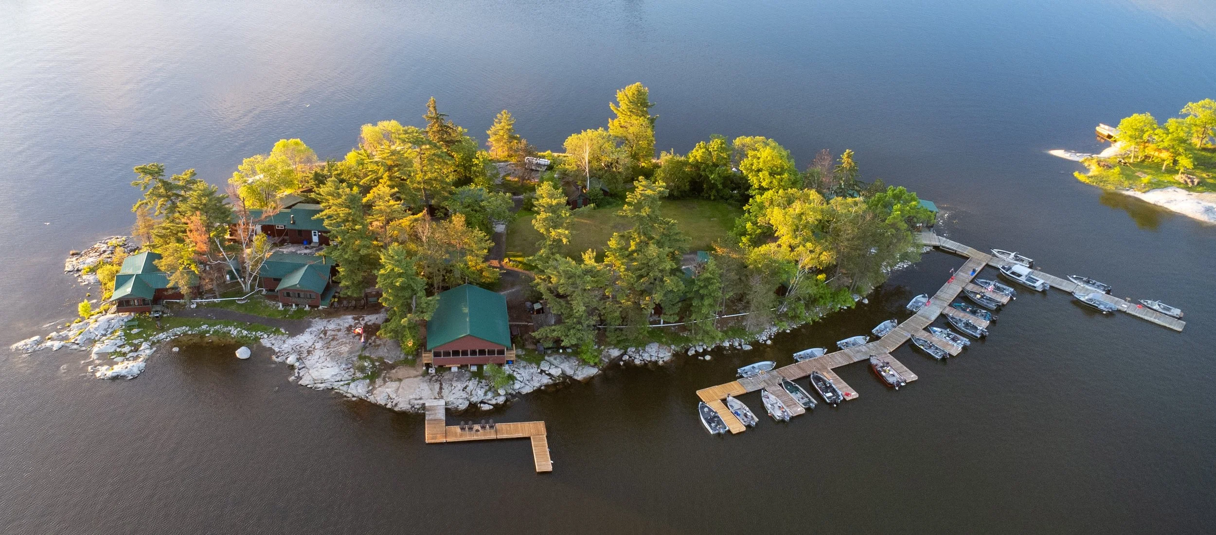Aerial view of Tamarack Island Wilderness Lodge featuring waterfront cabins, docks, and boats on Lake of the Woods near Morson, Ontario