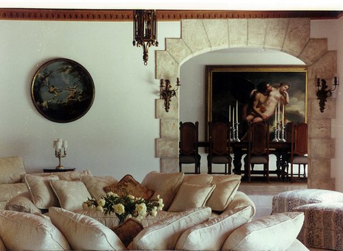 Living room with pale upholstered seating and artwork beyond an open doorway