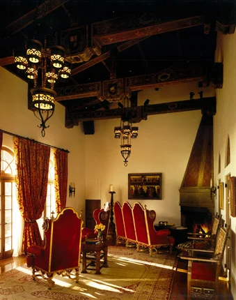 Double-height living room with exposed wood beams and red upholstered chairs