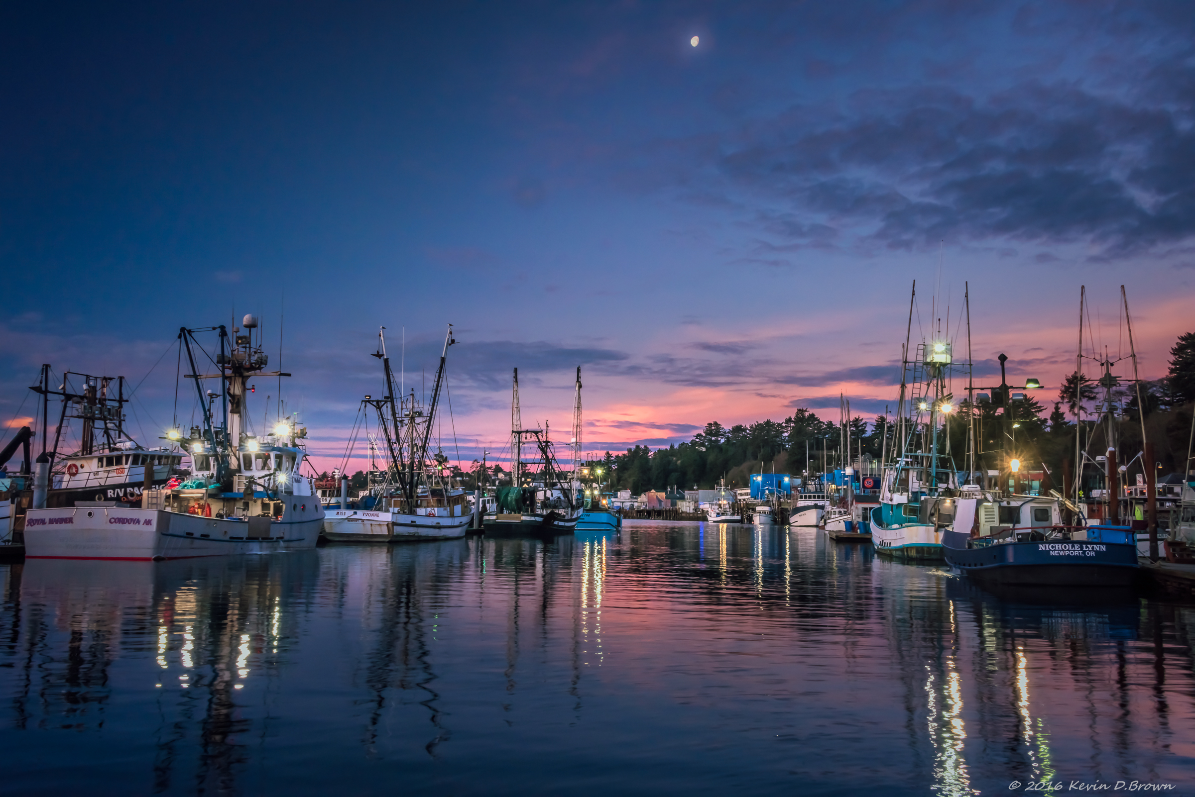 The moon falling in the sky as the sun begins to rise on Yaquina Bay in Newport, Oregon