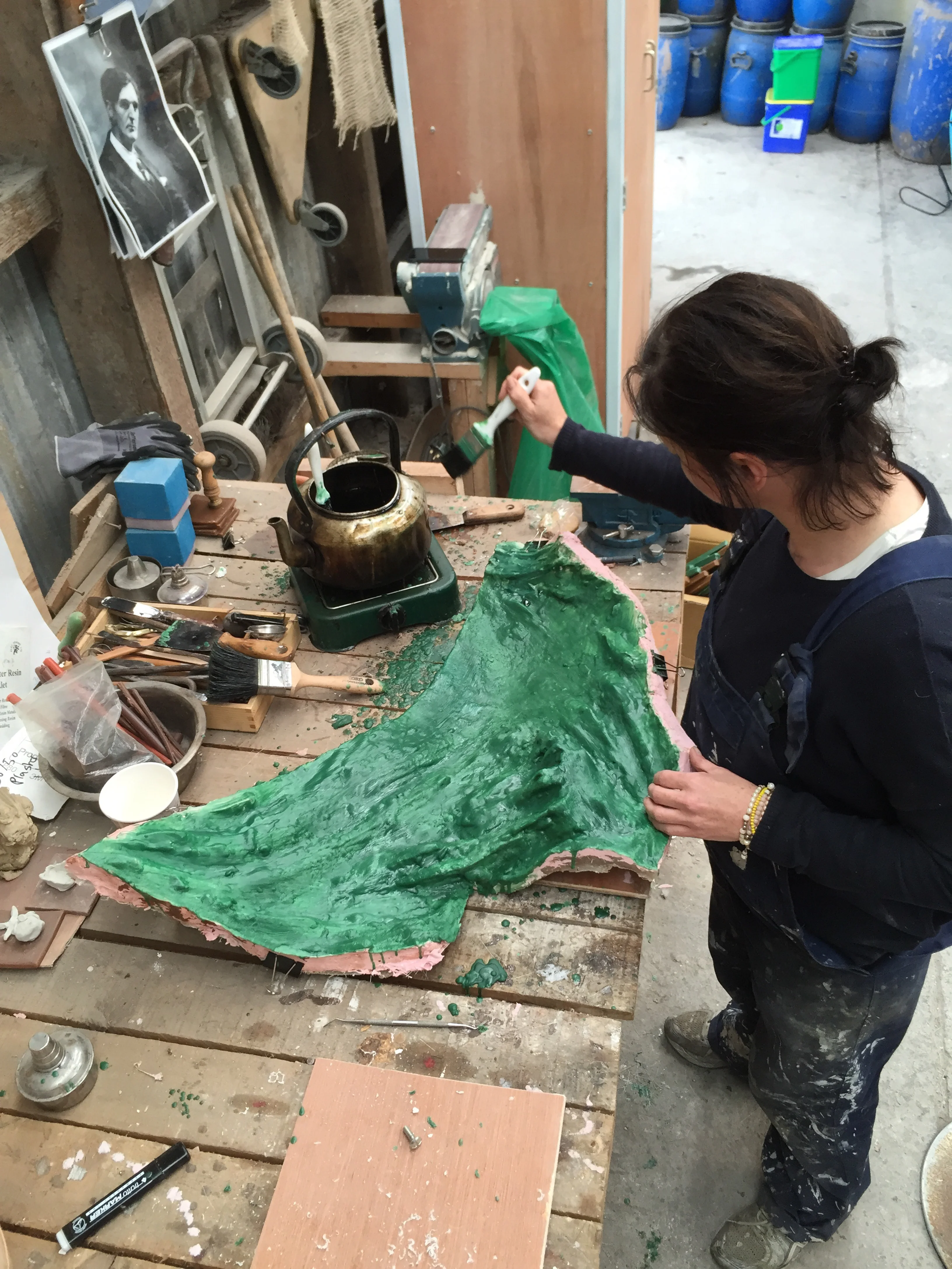 Karen is brushing molten foundry wax into a mould section. Note the photo of a young William Conor on the wall...