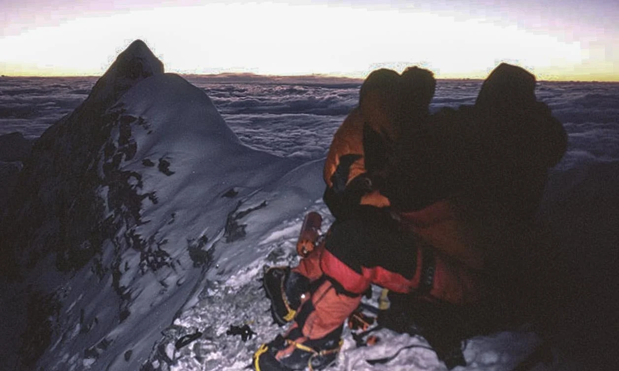 Myles Osborne's climbing guide, Dan Mazur (Red coat), and CLIMBER Lincoln Hall (orange) shortly after Osborne's team discovered Hall on the mountain. Hall was hallucinating, and trying to pull him off the 10,000 foot drop pictured. (Photo by Andrew Brash)