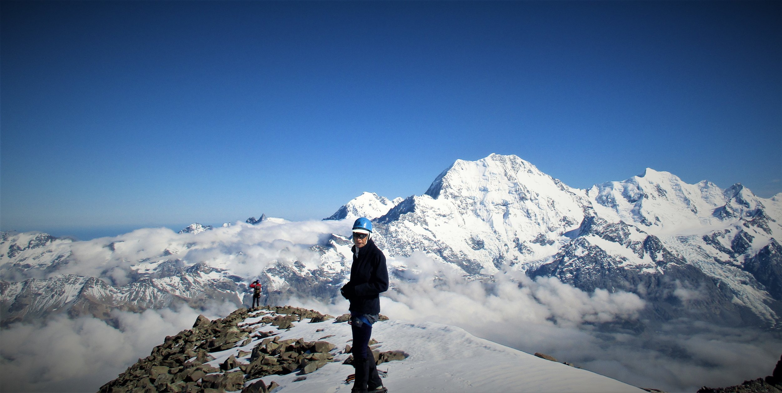 Ben looks into the Camera as George takes in the view of La Perouse, Aoraki,/Mt Cook and Mount Tasman from the large summit of the Nun's Viel.