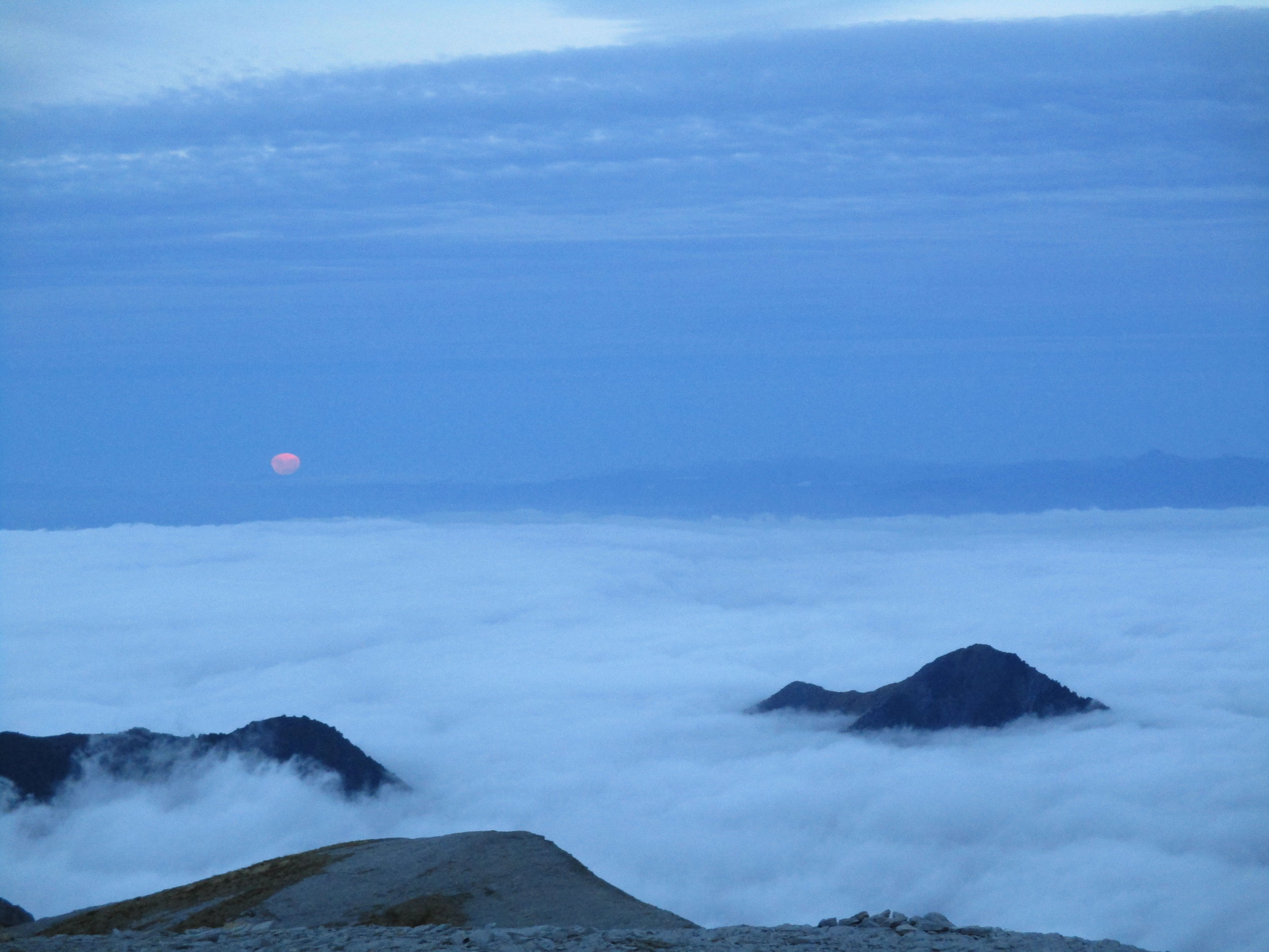 A full moon rising above the clouds.
