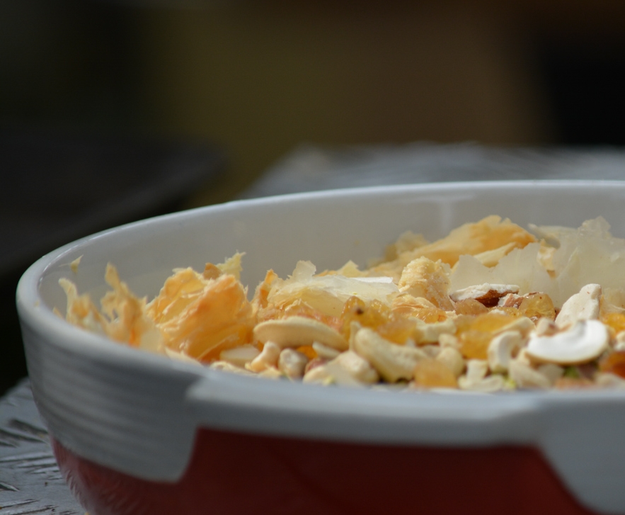 Start with your crushed pastries, nuts, and fruit in a baking dish.