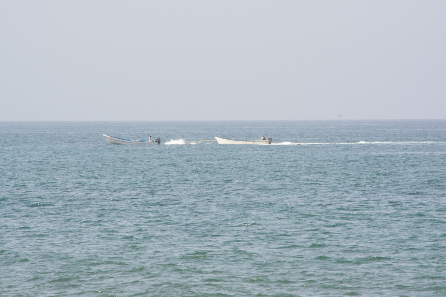 Two boats pointing left with their engines roaring, but traveling right.