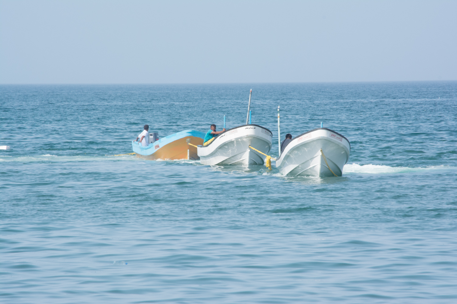 Waiting on the beach for boats that struggle against the weight of the net.