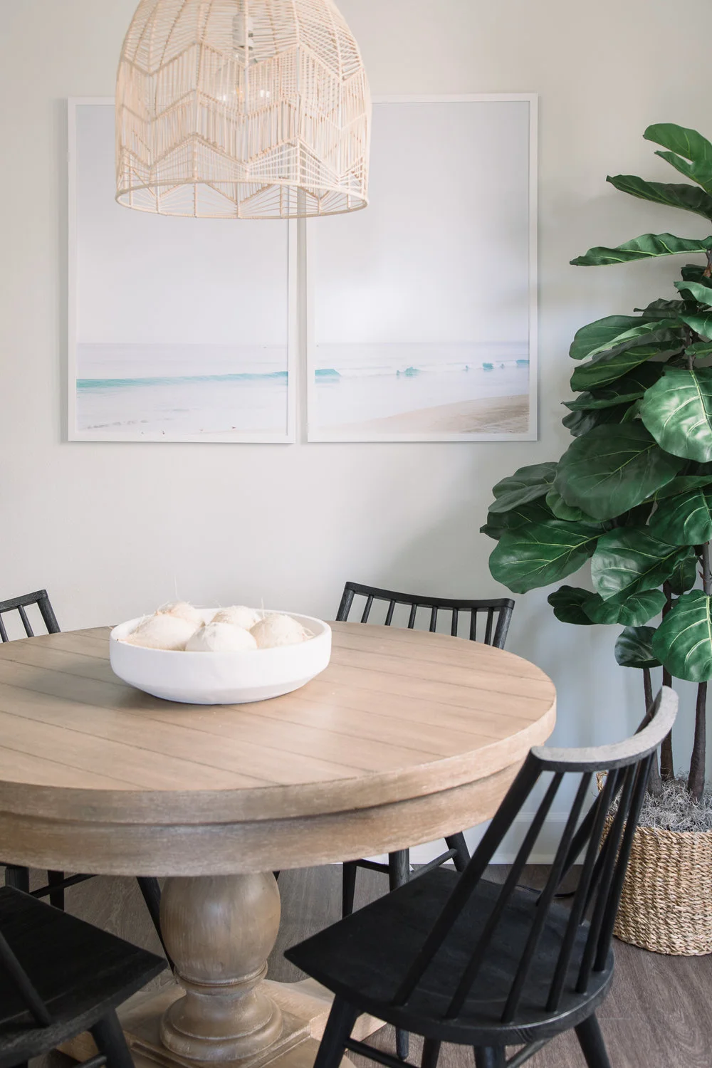 The white pendant light floats dreamlike above the table, anchored by delicate black chairs.