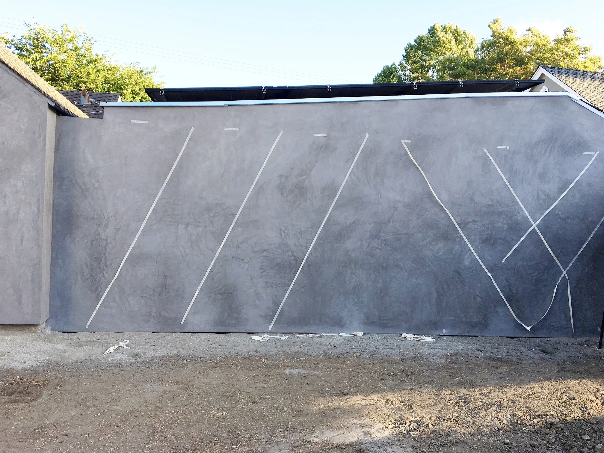 Here's what its looking like now. We covered both walls with stucco so it feels cleaner and more consistent. Next, we are going to espalier vines up the wall in a criss-cross fashion. Here's my lame tape job looking at different angles.