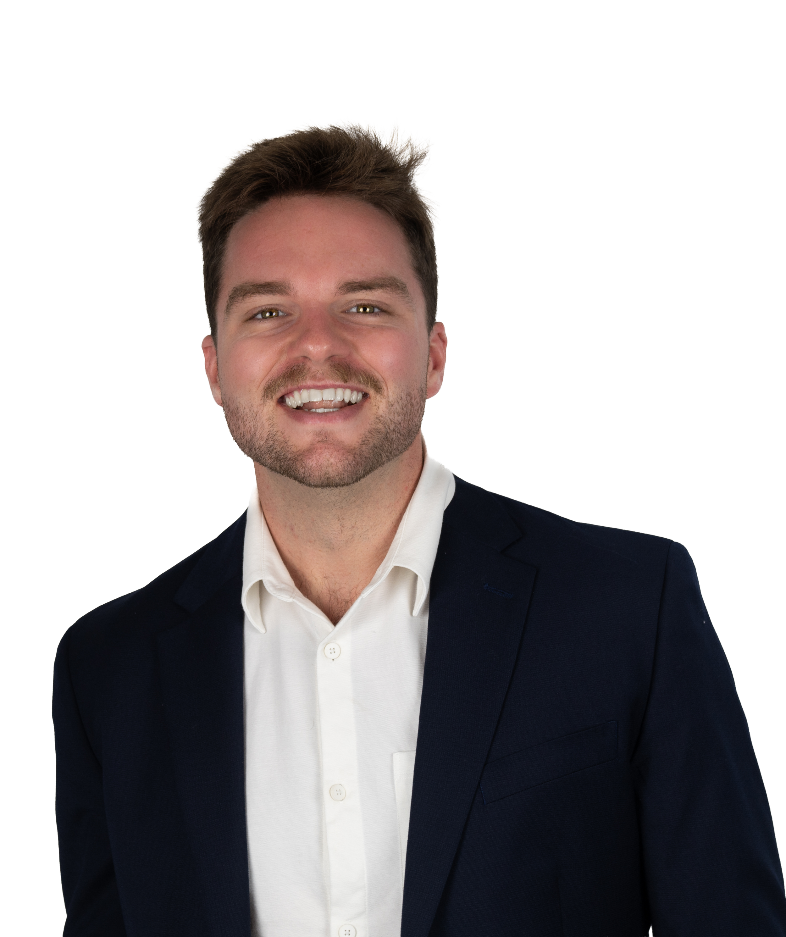A smiling young man with short brown hair and a beard, wearing a dark suit jacket over a white dress shirt, standing against a plain background.