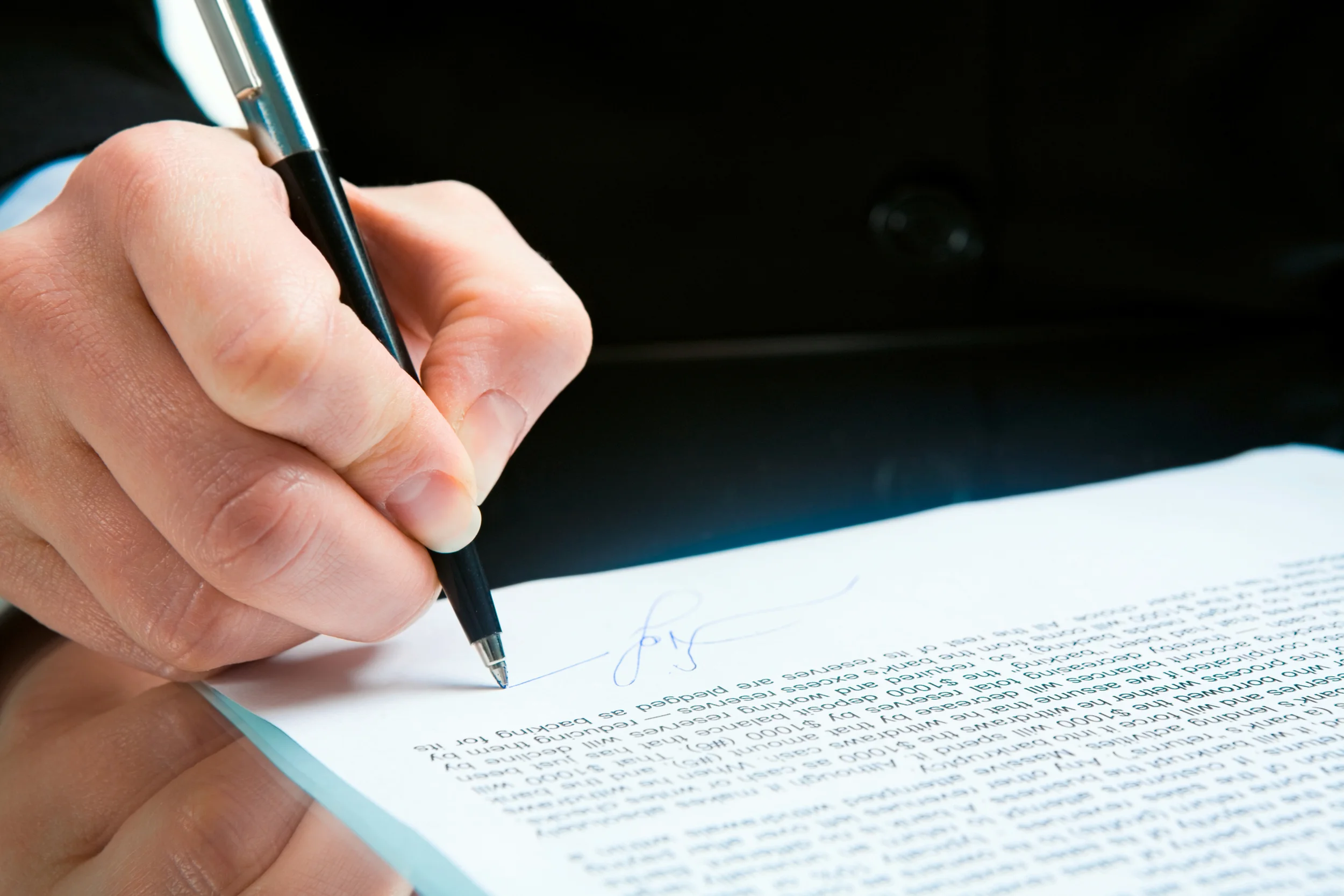 Image: close up of person's hand signing document. desert adr.