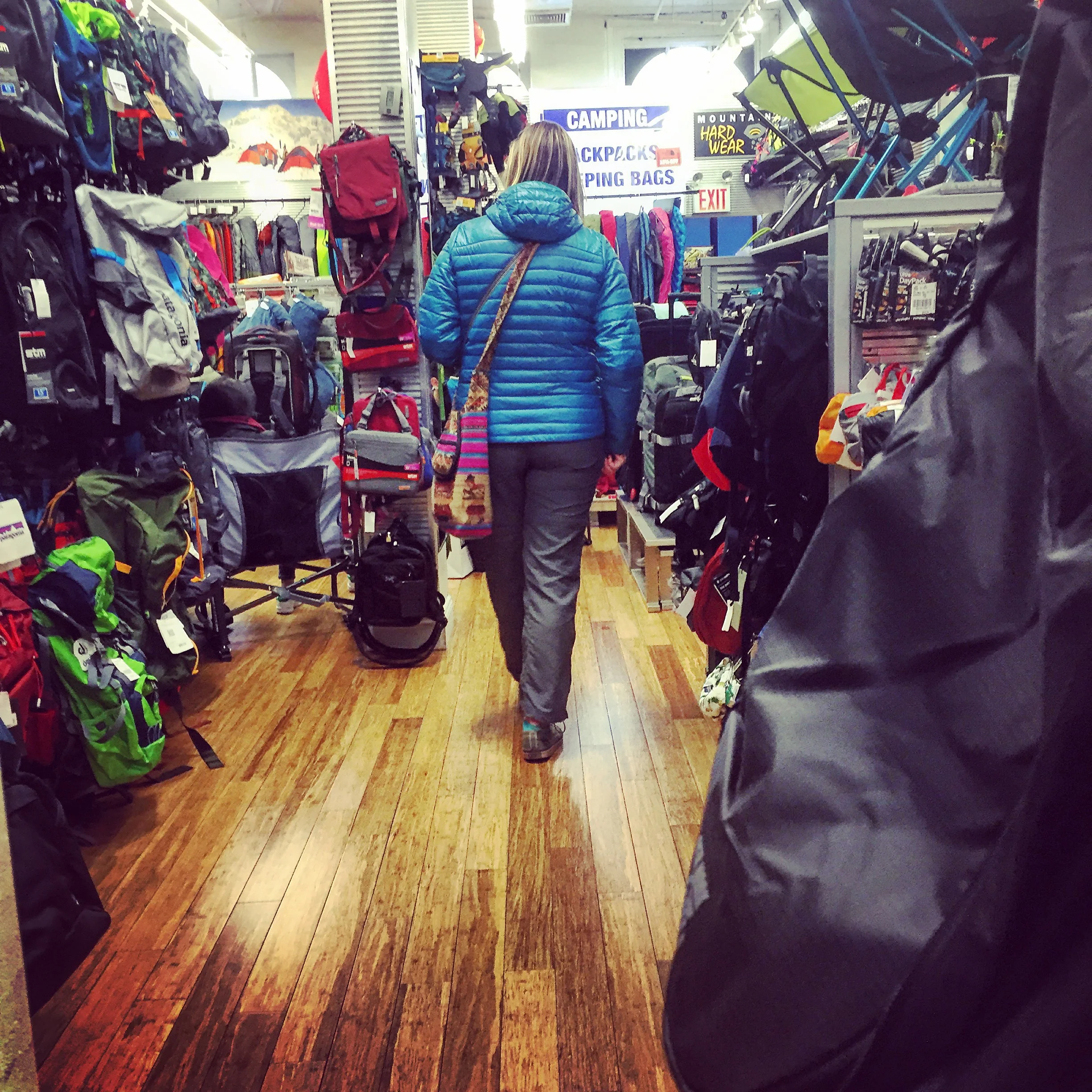 A customer inside the "Backpacks & Sleeping Bags" area of the store.