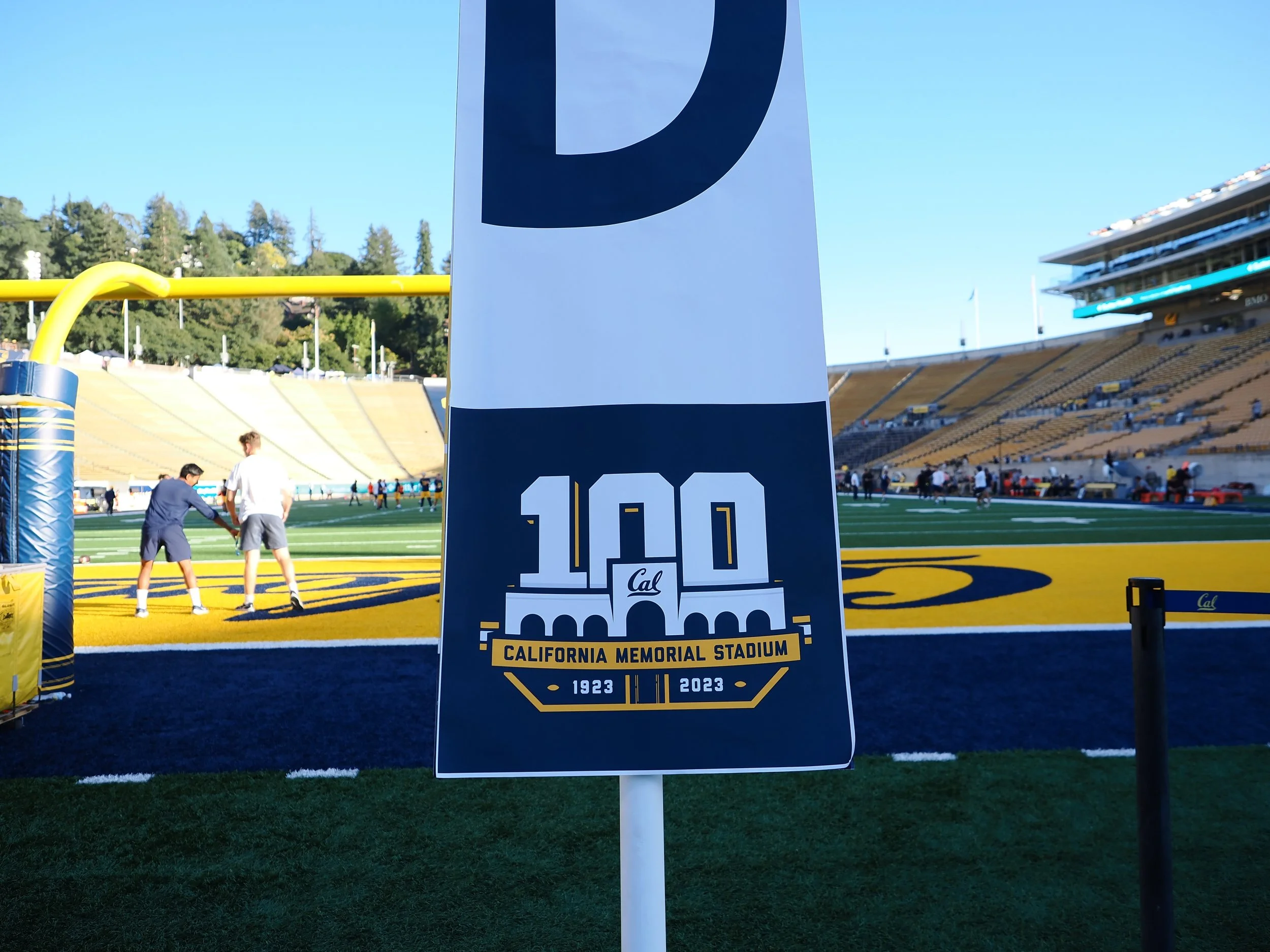A sign on a football field at California Memorial Stadium commemorates its 100th anniversary, with the years 1923 to 2023 and the stadium's logo in the foreground.