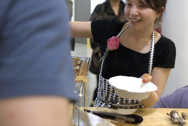 IMAGE - Gossiaux serving spaghetti into a handmade ceramic bowl. Emilie Gossiaux, Spaghetti Night , 2014. Image courtesy the artist.