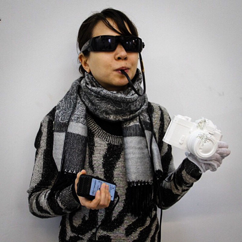 IMAGE - The artist wearing her BrainPort device, holding a ceramic mold of a camera.