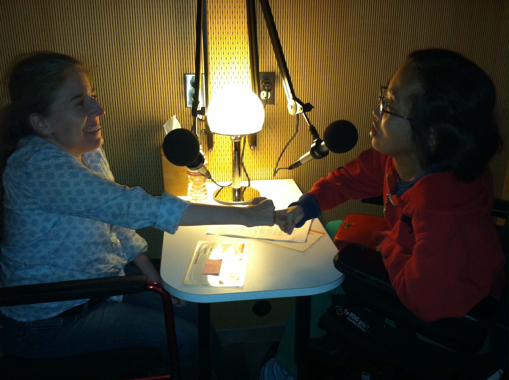 IMAGE - Fist-bumping during an interview at StoryCorps San Francisco with Ingrid Tischer (left), Director of Development, DREDF and Alice Wong (right), Head Honcho, Disability Visibility Project, 2014. Image courtesey Alice Wong, DVP.