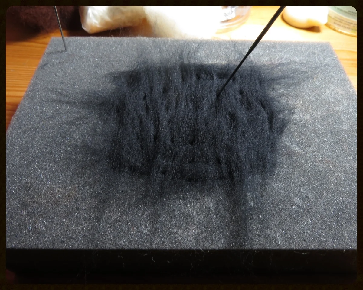 3. Needlefelt the layers together, poking the needle in at different angles so the two layers are firmly stuck together. Fold the wispy bits sticking off the edge back into the rectangle and needlefelt those in place.