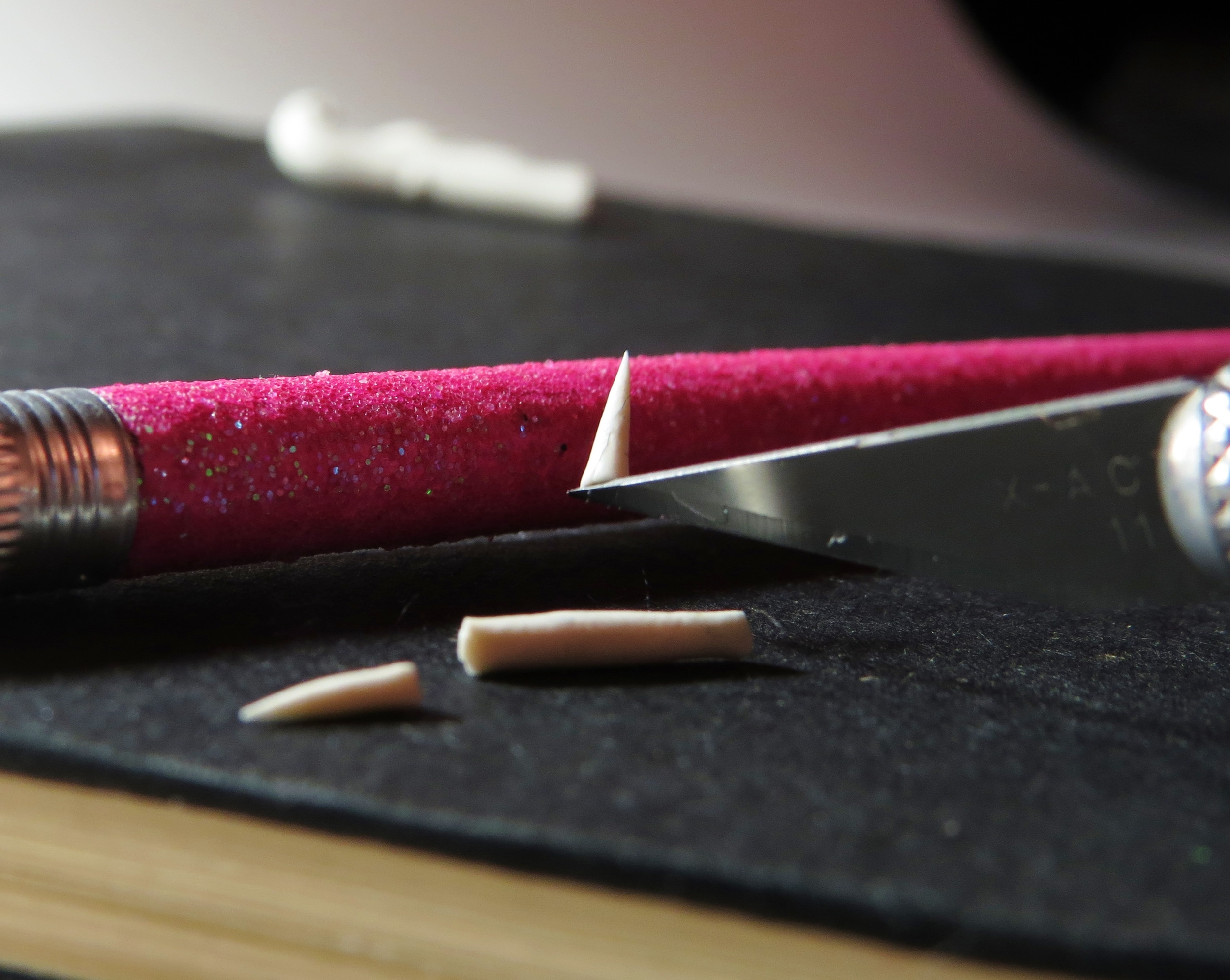 3. Using an X-ACTO knife (the sharper, the better), cut identical claws from either side of the roll. Saw back and forth a little as you cut; that way, the base of the claws will not flatten. Use the blade to pick up the tiny claws (see how the claw sticks to the blade?), then brush the claws gently onto whatever surface you'll eventually bake them on.