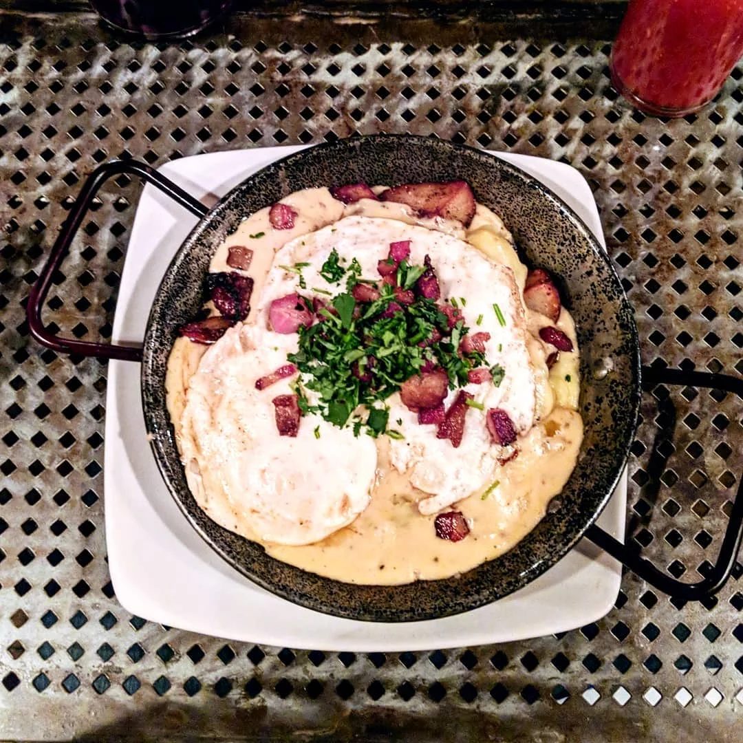 Breakfast Poutine: potato wedge home fries, cheddar curd, sausage gravy, eggs over easy, bacon crumble