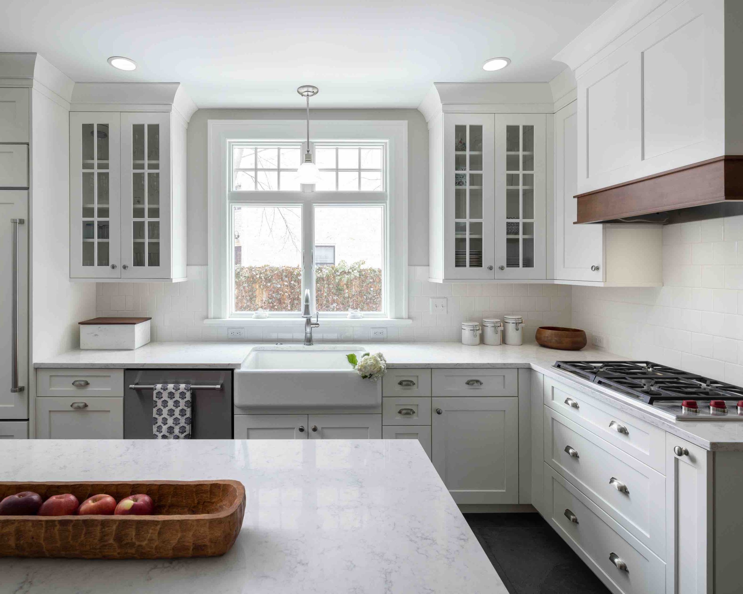 Kitchen with island, white cabinetry, and marbled stone countertops