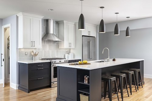 kitchen with range hood, contrasting cabinets, and pendants over island