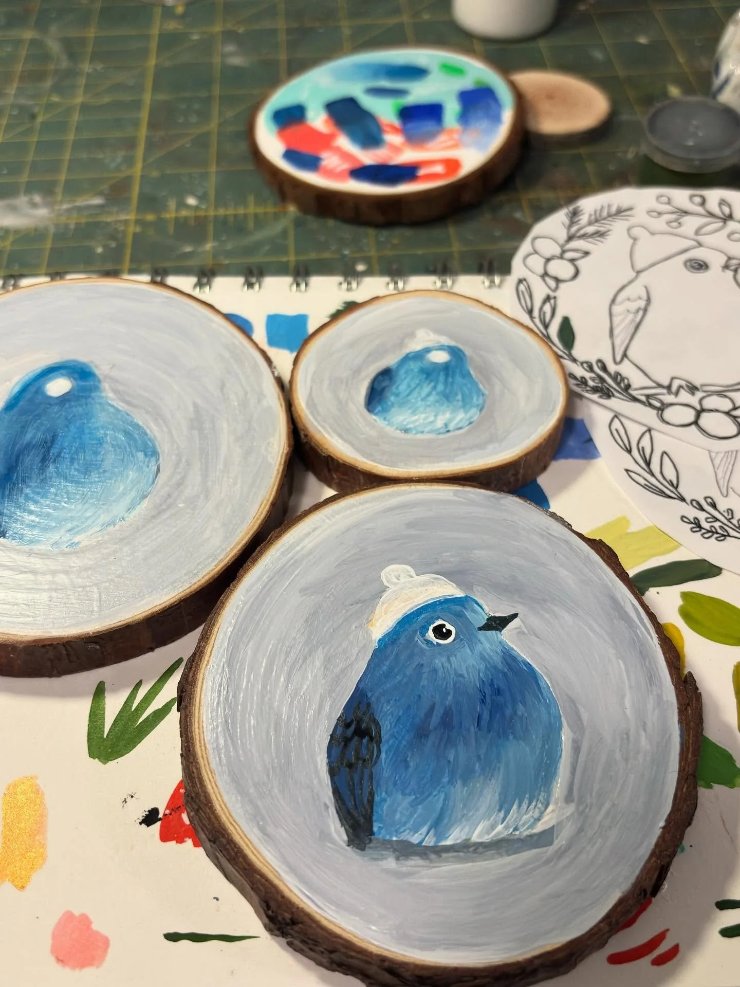 Blue blobs are turning into bluebirds. Gearing up for market season starting in three weeks!. 

#marketseason #woodsliceornament #gouachepainting