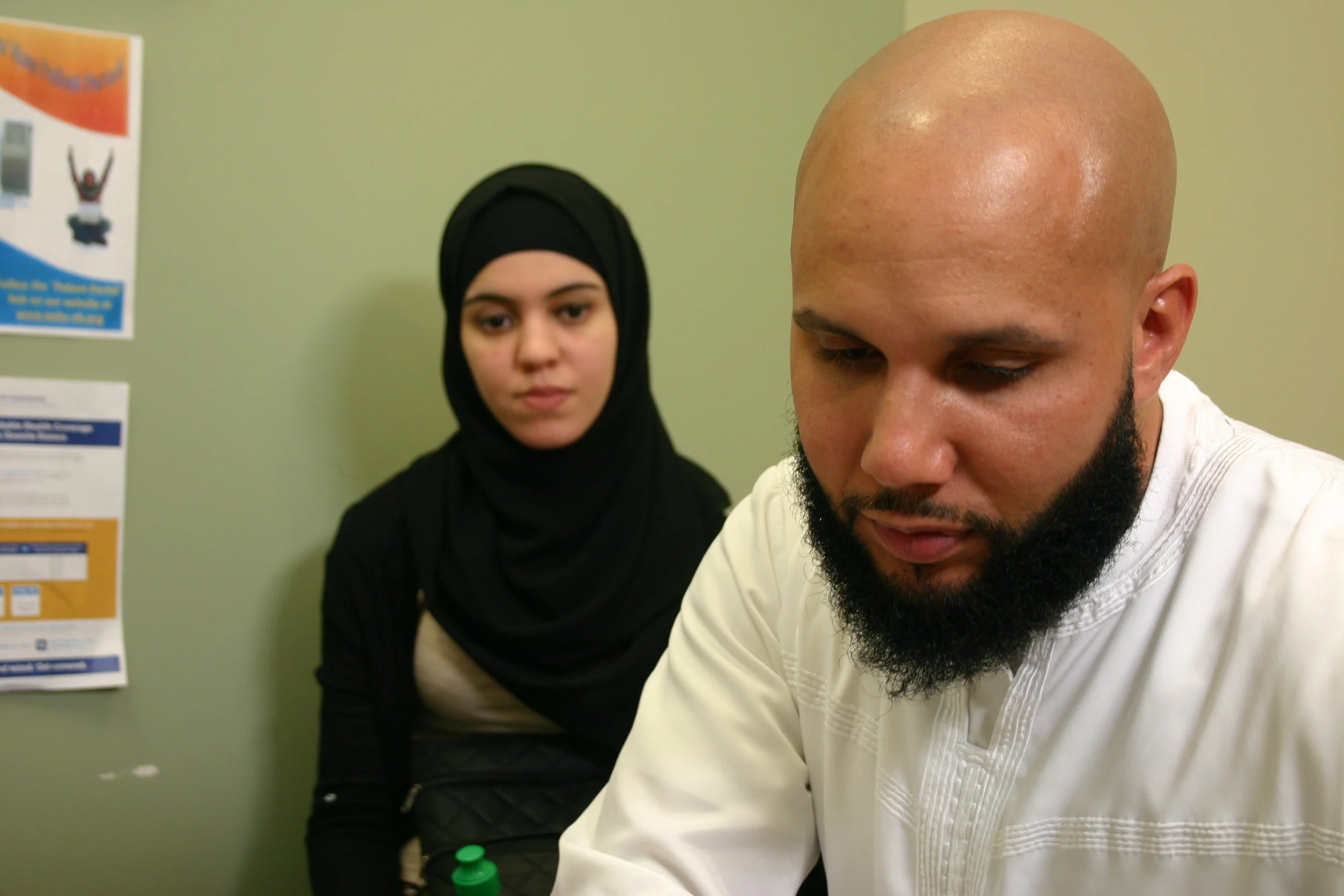   Yusuf and Imane Valera sit with a social worker at Manchester Community Health Center to fill out an application for the state's expanded Medicaid program.&nbsp;  