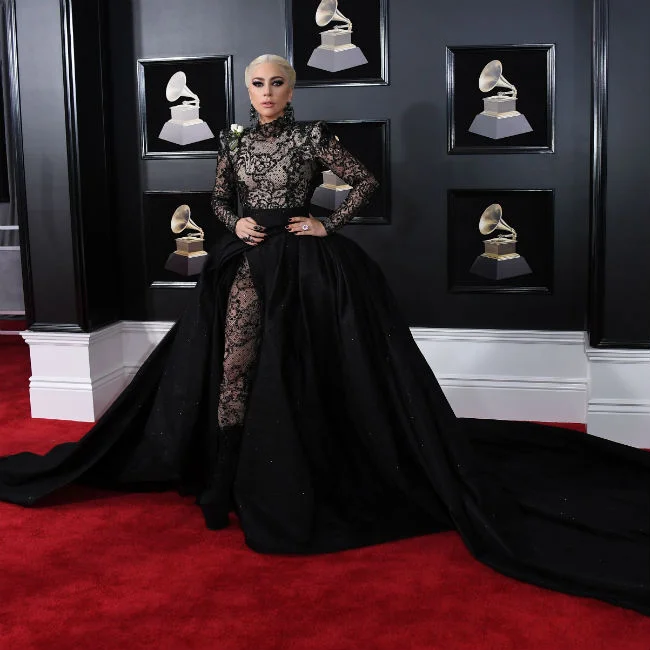 Lady Gaga wearing an embellished bodysuit with thigh high slit ball gown skirt by Armani prive. She ditched the skirt and wore just the sheer bodysuit once she arrived inside. She accented her look with Lorraine schwartz jewels. 