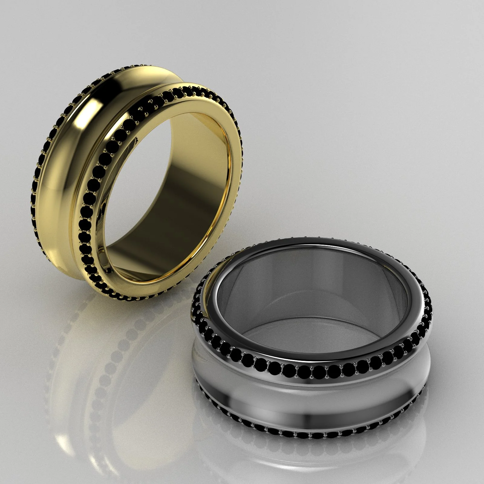 Two wedding bands, one gold and one silver, decorated with black gemstones, placed on a reflective surface.
