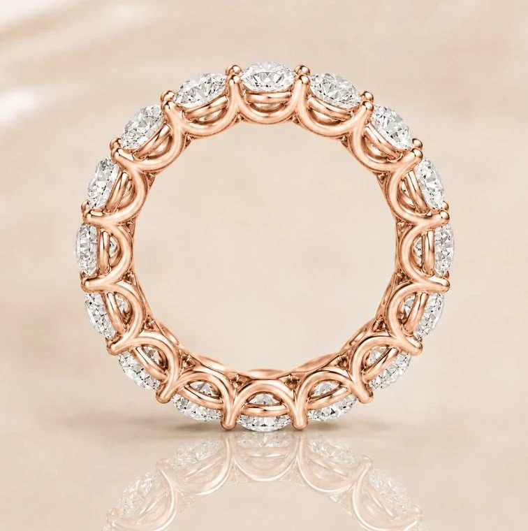 A rose gold circular ring with embedded diamonds, featuring intricate design details.