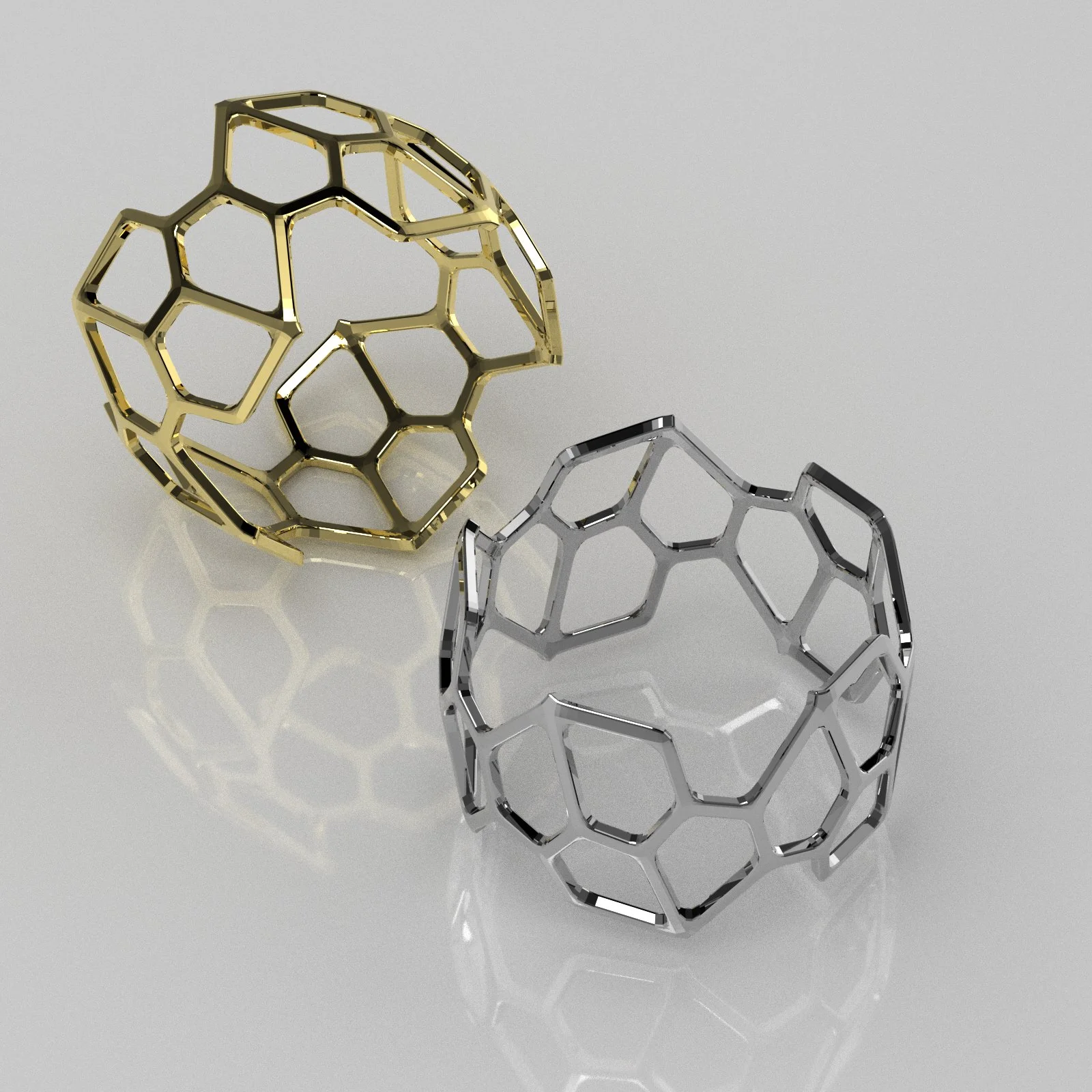 Two metallic hexagonal cage-like objects, one gold and one silver, positioned on a reflective surface, with the gold one standing upright and the silver one lying down.