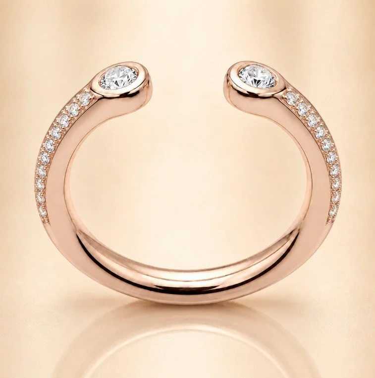 Rose gold open cuff bracelet with embedded small diamonds on top and a larger diamond at each end.