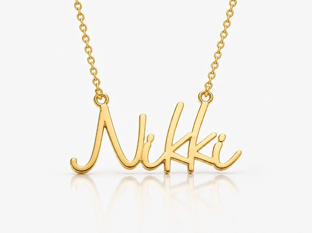 Gold necklace nameplate that spells out the name "Nikki" in cursive script.