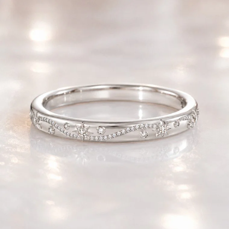 Silver bracelet with star and round diamond accents on a reflective pearl surface.