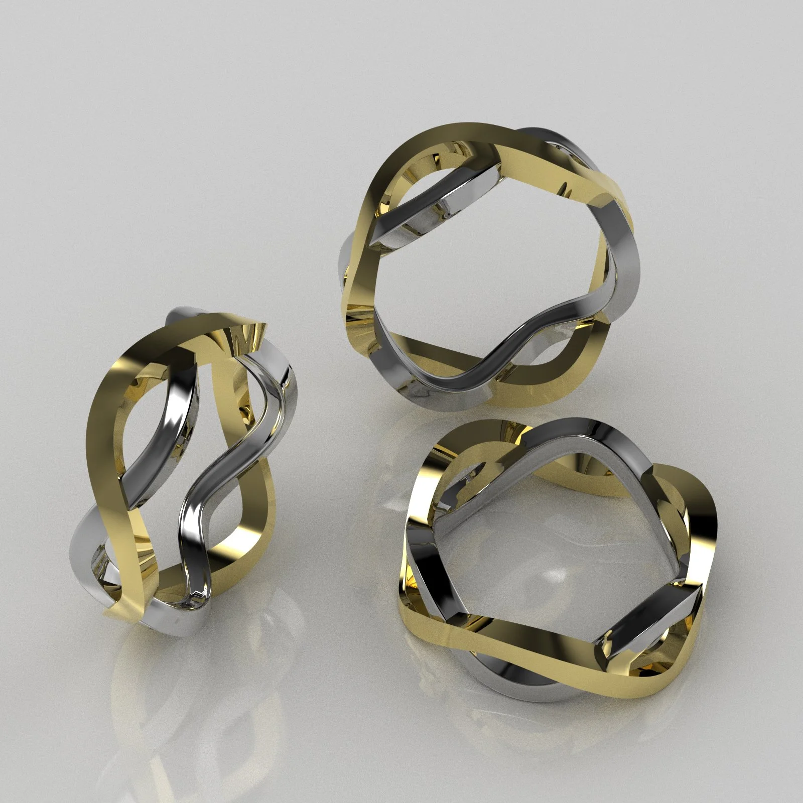 Jewelry rings in black, gold, and silver with a geometric design, arranged on a light-colored reflective surface.