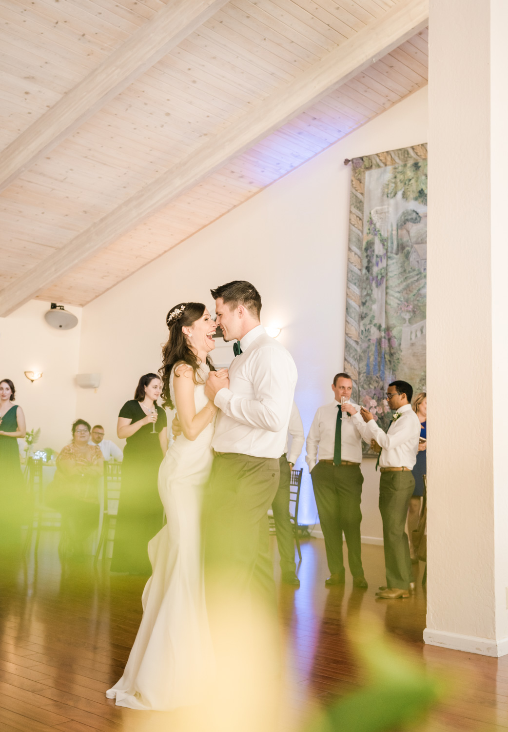 First dance picture with people behind the groom and the bride.The green shadow you see is the deliberate use of leaves to add some fun.
