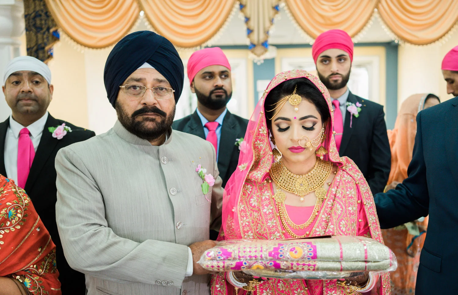 Father of the bride walks her down the aisle inside the gurudwara.