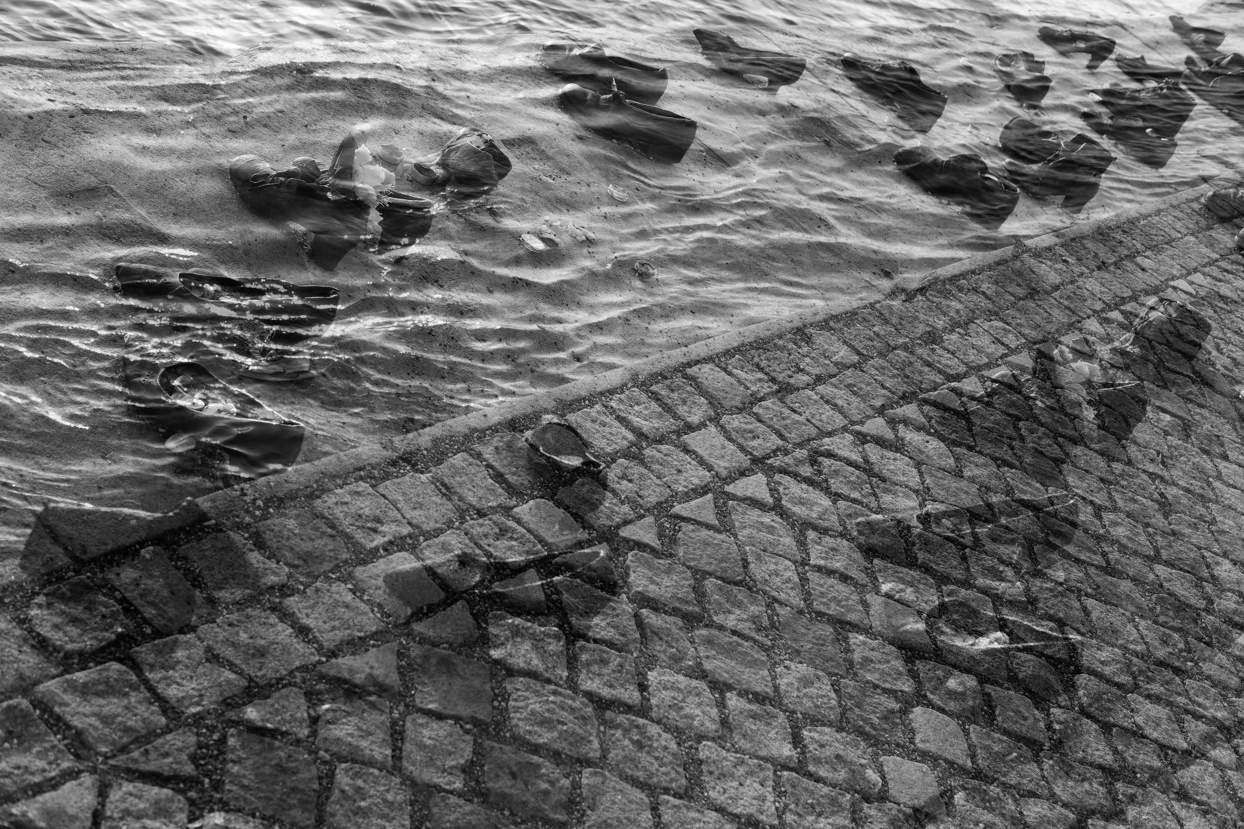 Jewish persecution during WW II. About 100 Jews were tethered together and taken to the banks of the Danube. 2 or 3 of them shot, falling into the river and pulling the rest with them to die by drowning. This is a double exposure of an art installation: cast iron shoes along the banks of the Danube.
