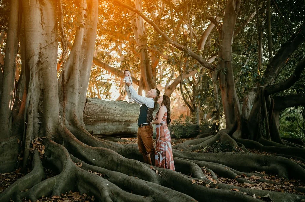 Family holding their infant with banyan trees as a backdrop