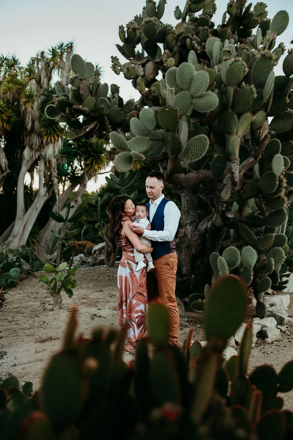 family cuddling their baby in cactus garden