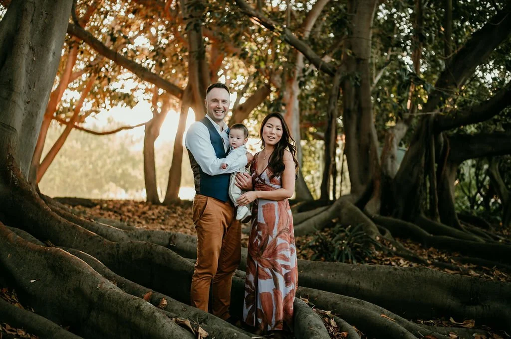 Family holding their baby standing in the banyan trees at south coast botanic gardens in South Bay Los Angeles