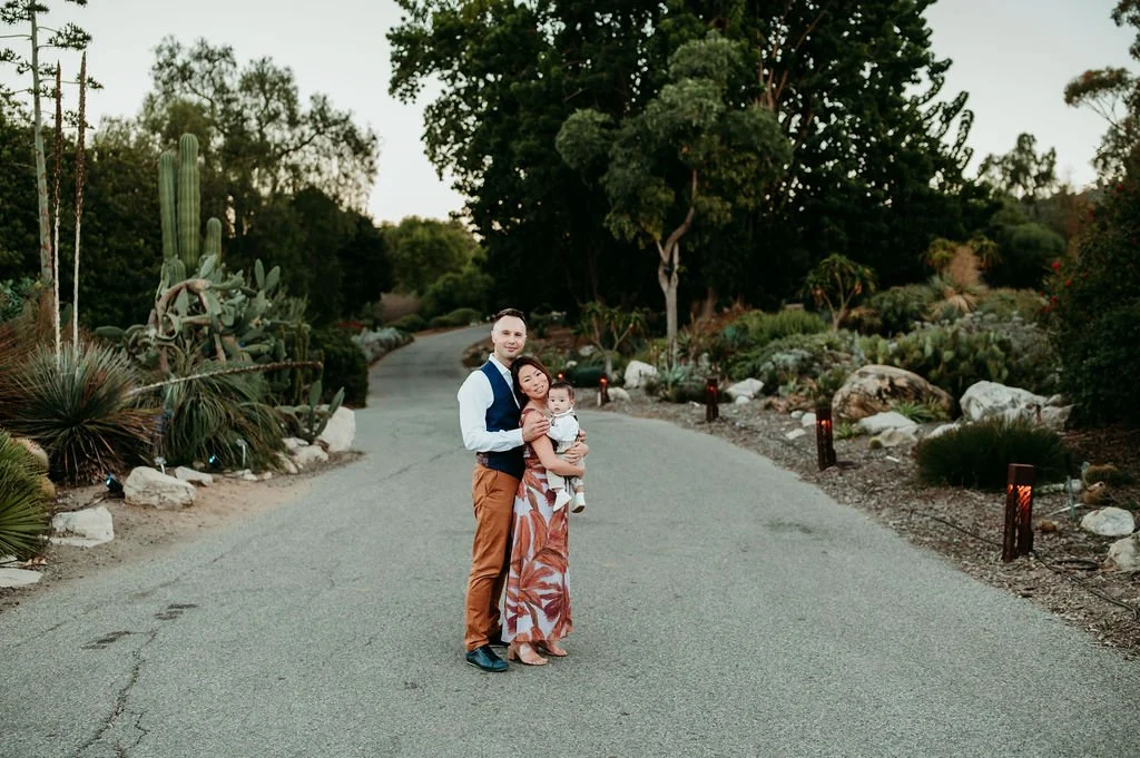 parents holding their infant on garden pathway