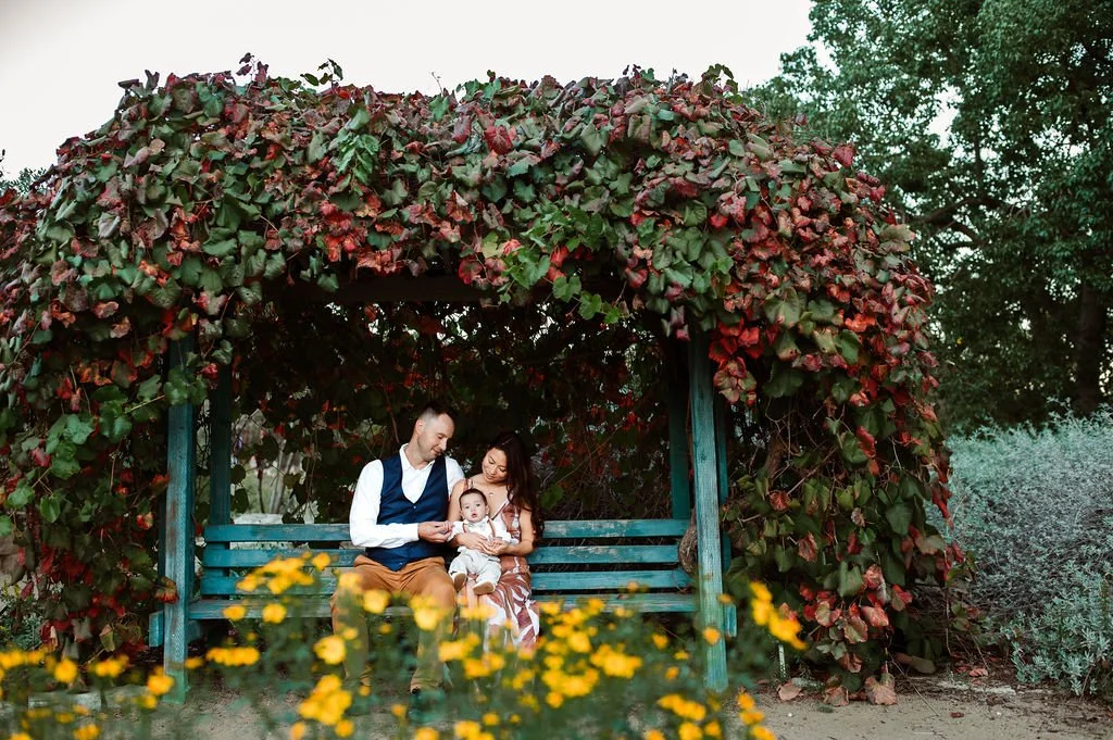 Family holding their child on a bench filled with a beautiful array of flowers