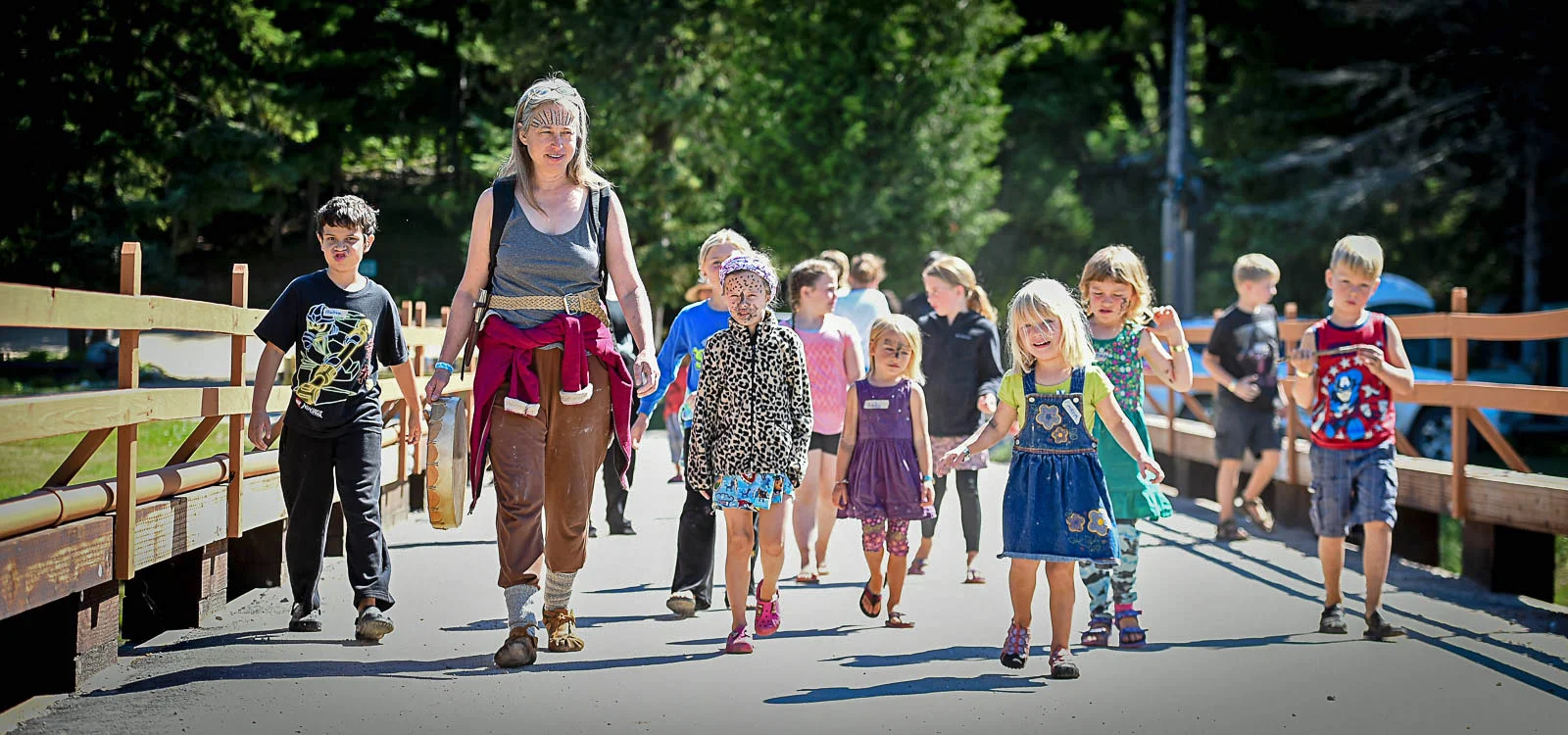 Rowena Conahan leads a pack of children across a bridge spanning the Pigeon River, as part of the interactive Family Forest Village program at YogaFest 2017.