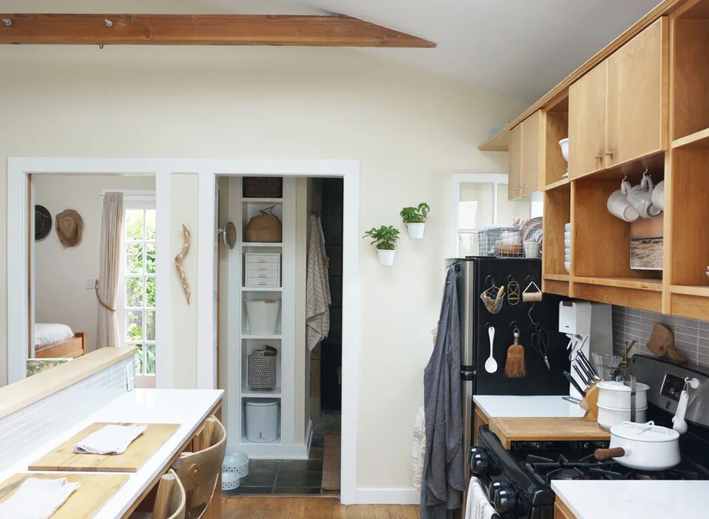 Above: The back tiny cottage kitchen, with herbs planted in wall pots near a window.
