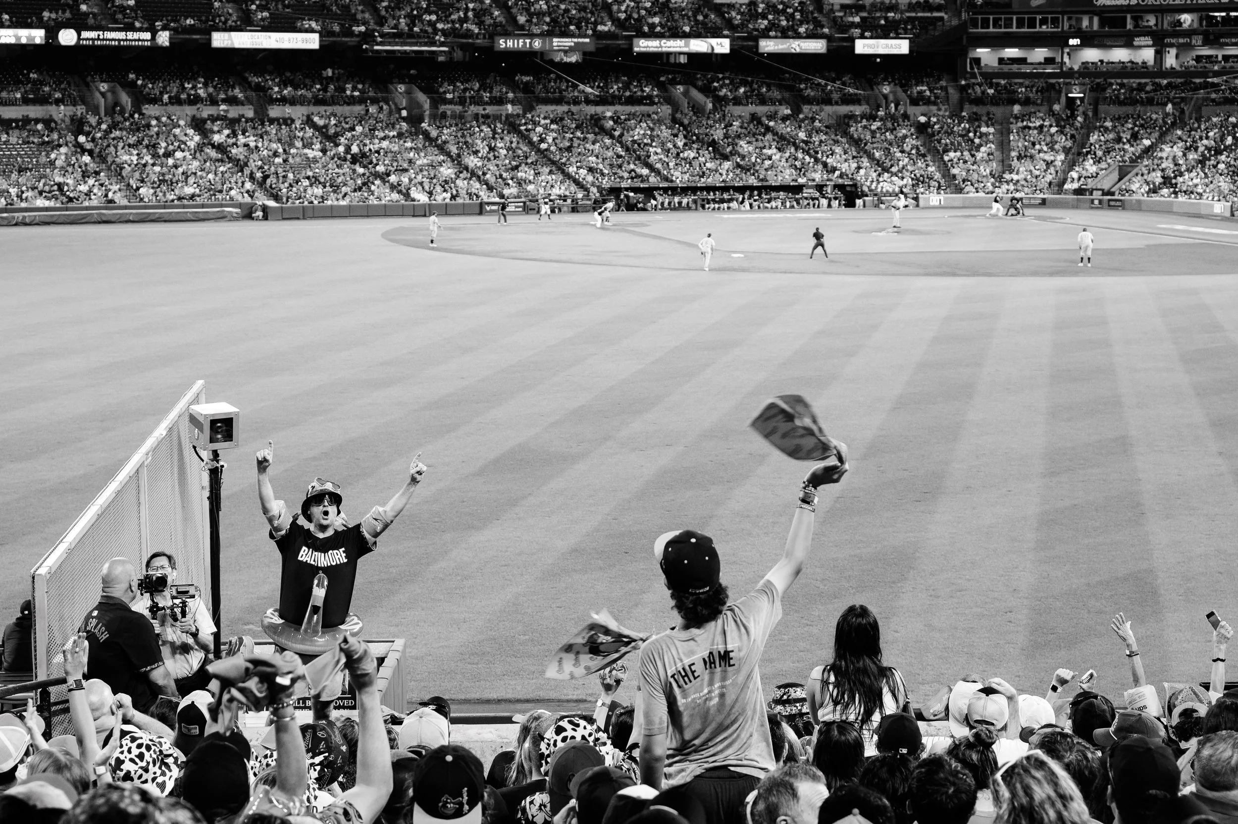 Crowd of baseball fans cheering as a player crosses home plate with teammates and fans celebrating in a stadium.