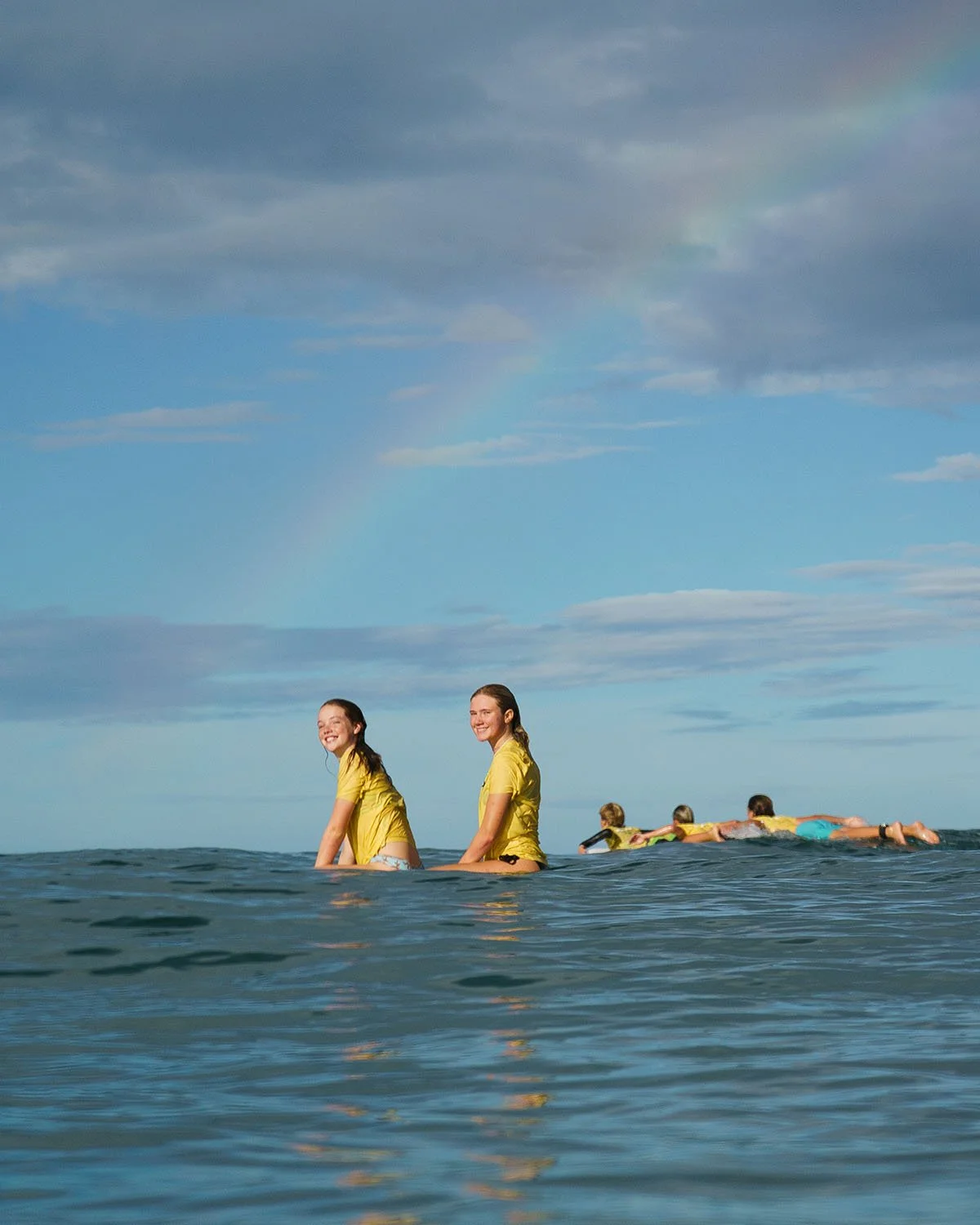 Teens relaxing in the ocean with a rainbow behind them during Discover Term