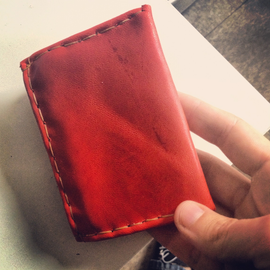   hand-sewn leather wallet, from one piece of leather, folded, with sinew thread  